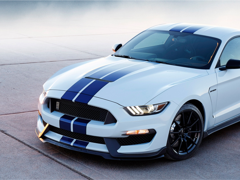 White Mustang with two dark blue racing stripes down the middle
