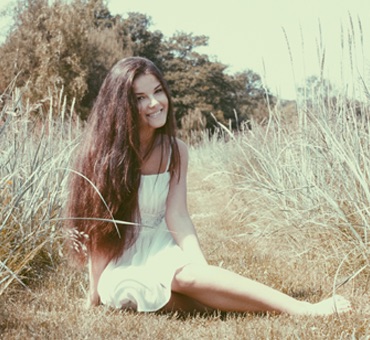 Girl with Long Brown Hair Sitting in a Field