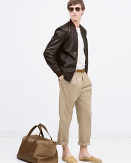 Man with Black Leather Jacket Overtop White Shirt, Khaki Pants with Brown Bag On the Floor